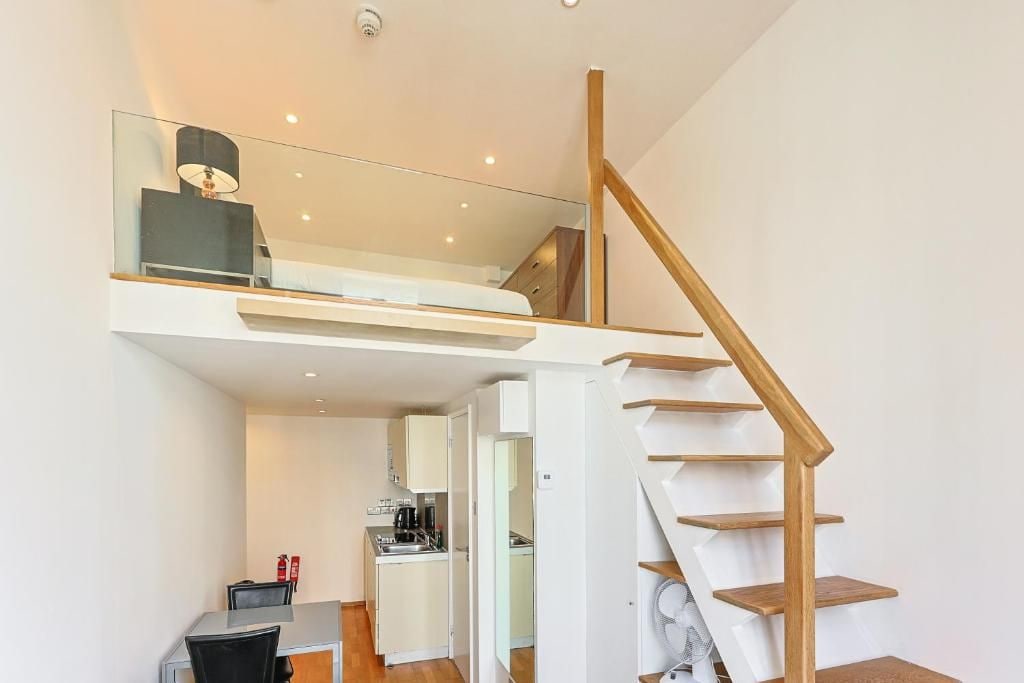 Ein modernes Interieur mit einer Treppe zu einem Schlafzimmer im Zwischengeschoss, einer Küchenzeile und einem Essbereich.