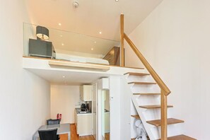 Ein modernes Interieur mit einer Treppe zu einem Schlafzimmer im Zwischengeschoss, einer Küchenzeile und einem Essbereich.