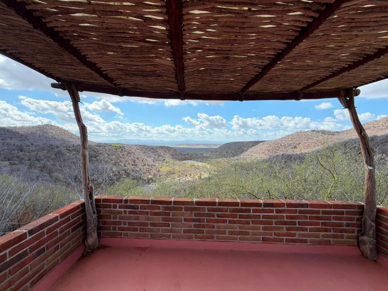 A covered outdoor area with a brick wall and a view of a valley.
