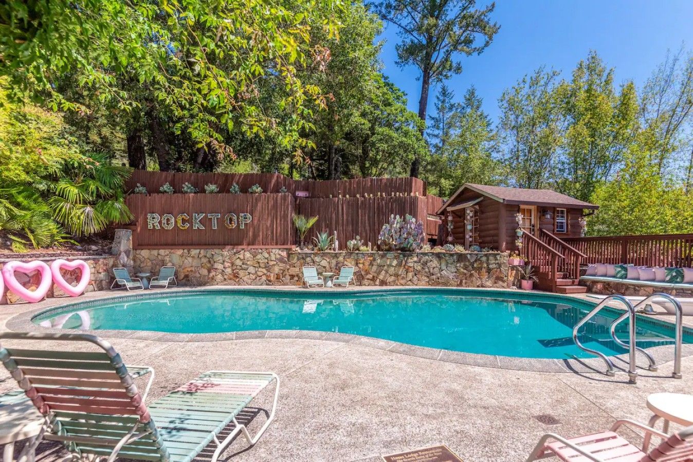 A pool area with a wooden deck, lounge chairs, and a cabin-like structure labeled 'ROCKTOP'.