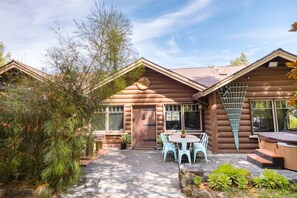 A log cabin with a patio, outdoor seating, and a hot tub.