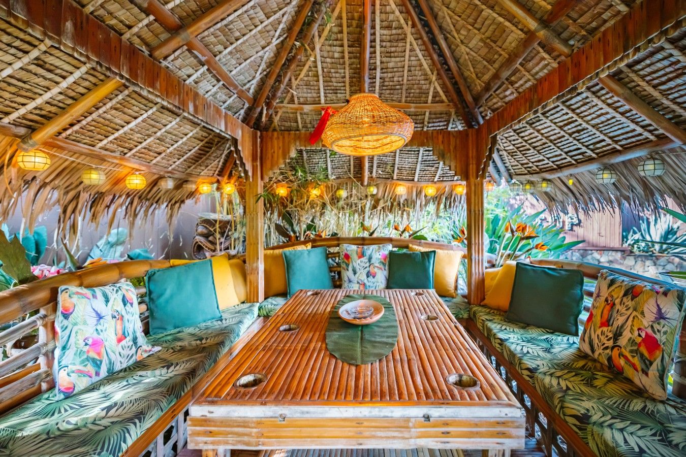 A thatched-roof interior with wooden furniture and hanging lights.