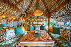 A thatched-roof interior with wooden furniture and hanging lights.