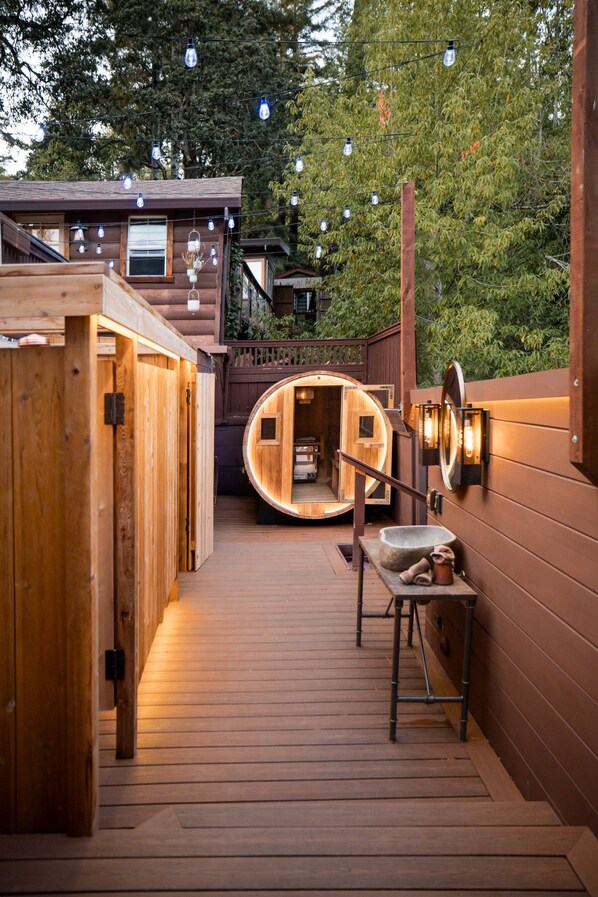 A wooden spa area with a sauna, a wooden bench, and a stone basin.