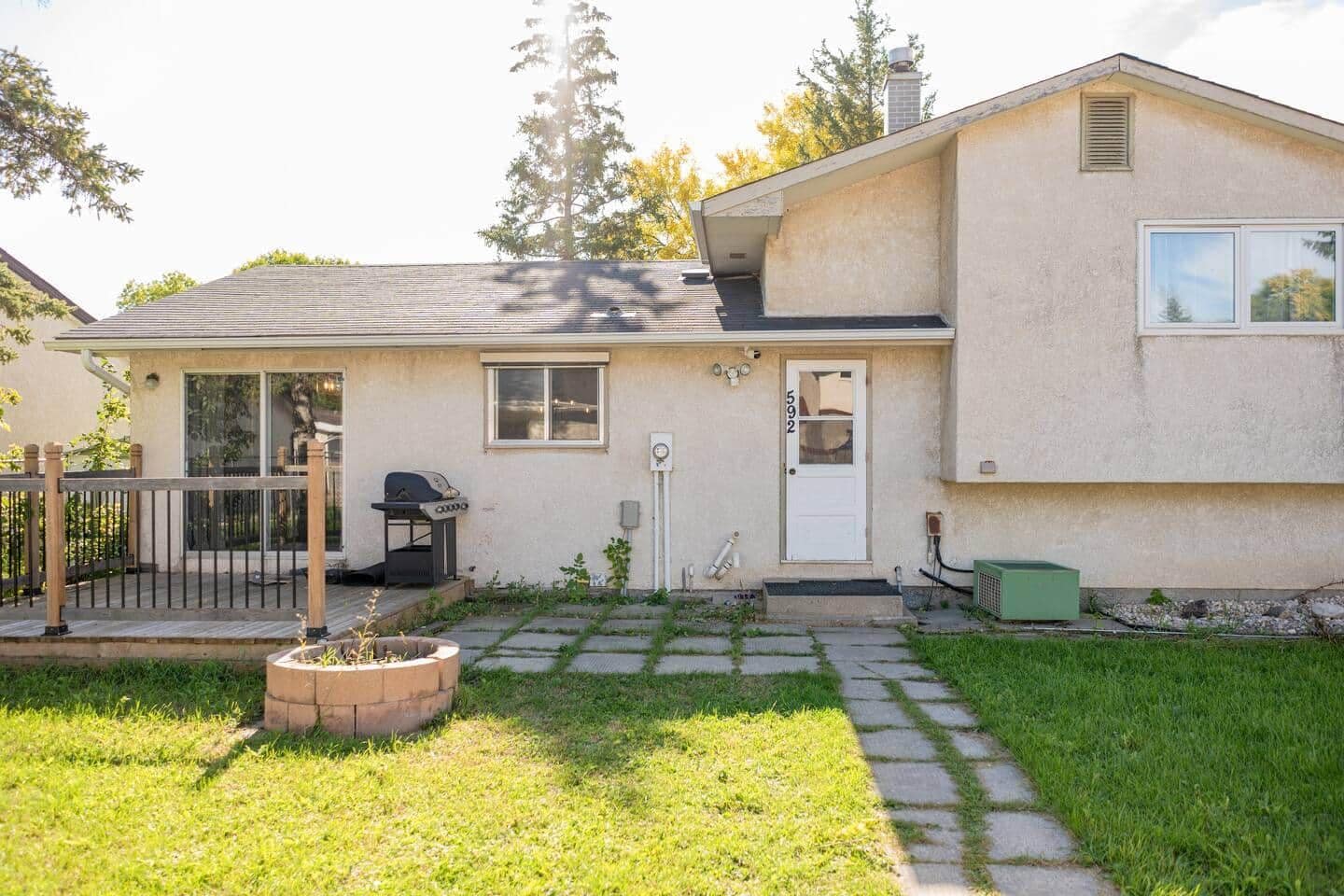A single-story house with a front porch, a visible garage door, and a small front yard with a lawn and a concrete pathway.