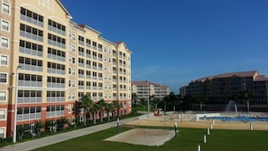 Um hotel com vários andares, varandas, um pátio ajardinado e área de piscina.