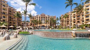 Um resort com piscina central, palmeiras e edifícios de vários andares.