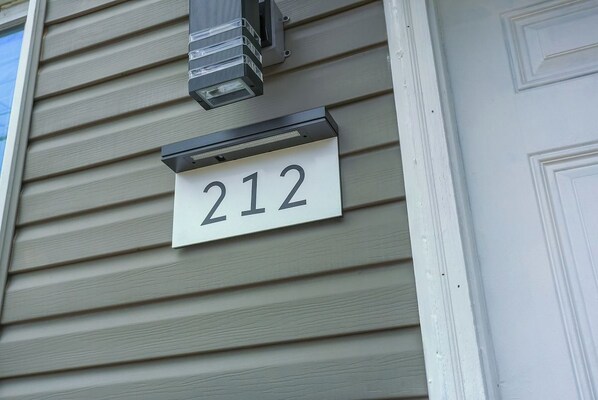 Un cartel con el número 212, montado en una casa con revestimiento.