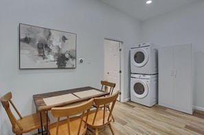 A room with a dining table, chairs, a wall-mounted abstract painting, a washing machine, and a wardrobe. - Carnegie, W Main St 208 A Cozy 2 Bedroom Private Apartment (Carnegie)