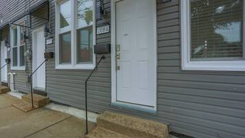 Una hilera de casas urbanas con revestimiento gris, puertas blancas y buzones numerados.