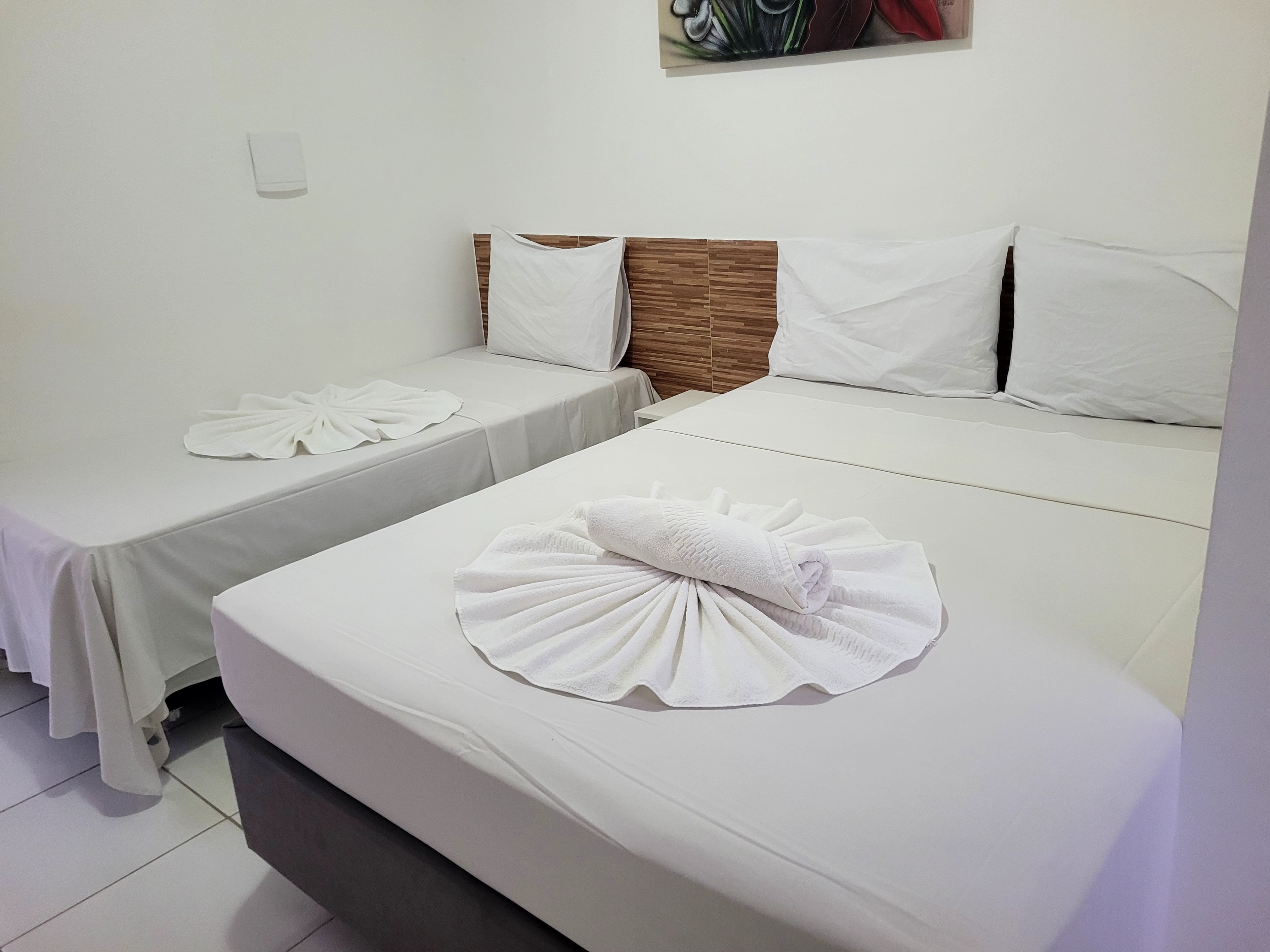 Una habitación de hotel con dos camas individuales, cada una con una toalla doblada y un almohadón.