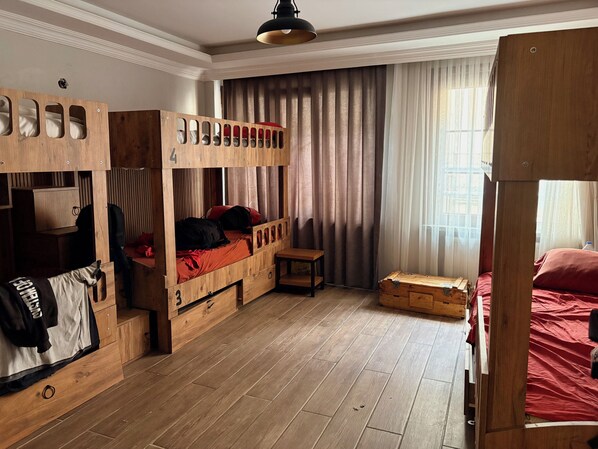 Una habitación con literas, un escritorio de madera y una ventana con cortinas.