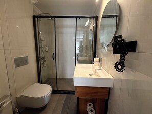 Casa de banho moderna com sanita, lavatório e zona de duche.