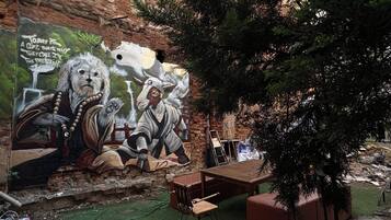 A mural with a lion and a figure, outdoor seating, and a brick wall.