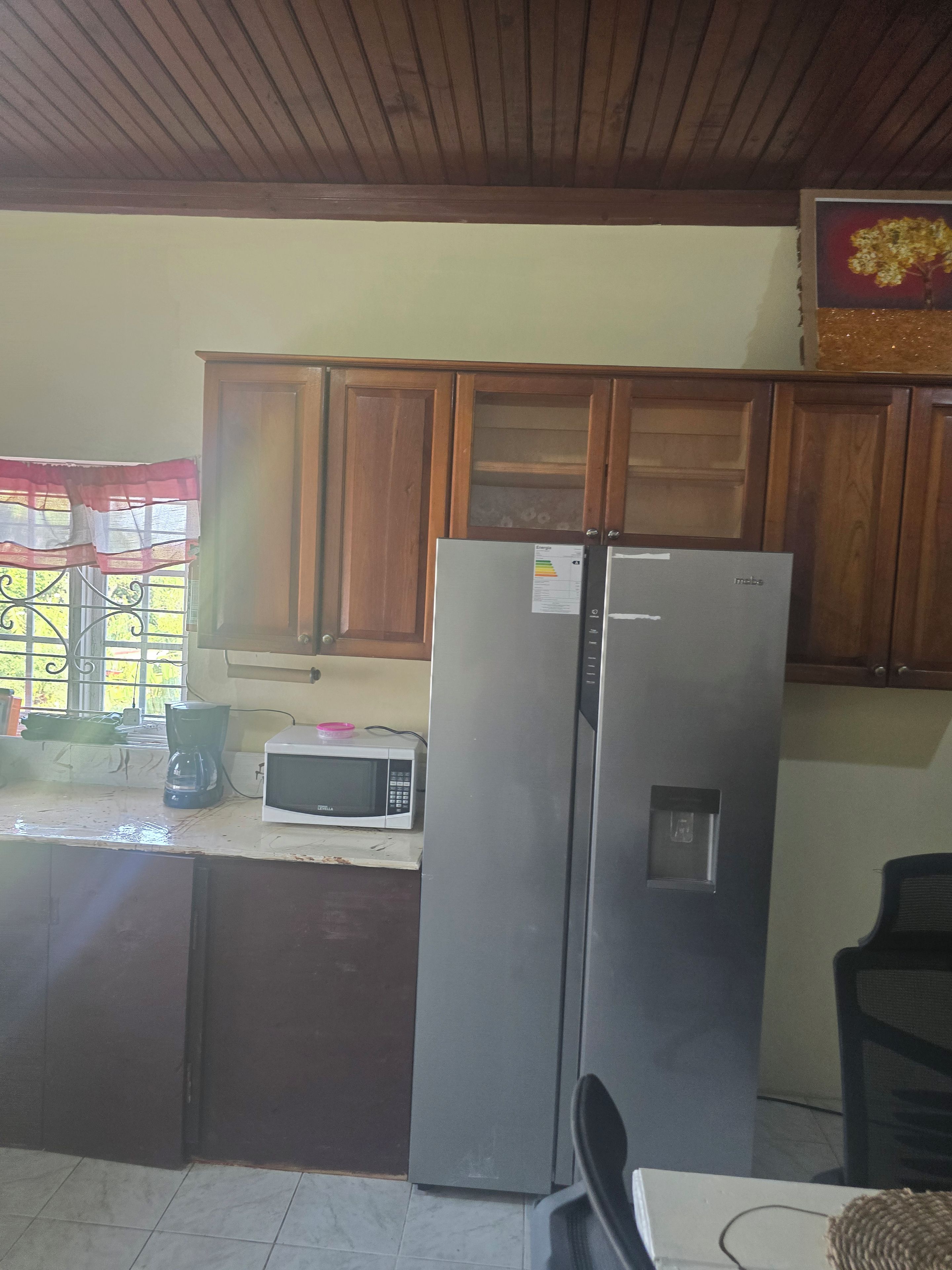 A kitchen with wooden cabinets, a refrigerator, a microwave, and a coffee maker.
