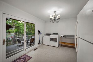 A compact kitchen with a built-in washer and dryer, a dining area with a glass door leading to a deck, and a chandelier. - NEW! Alpine Lodge | Large Home on 5 Acres | Near Alpine Camp & DeSoto State Park (Mentone)
