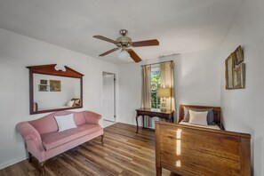 A room with a ceiling fan, a pink sofa, a wooden dresser, and a desk with a lamp. - NEW! Alpine Lodge | Large Home on 5 Acres | Near Alpine Camp & DeSoto State Park (Mentone)