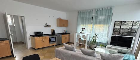 A modern living space with a dining area, kitchen, and seating area.