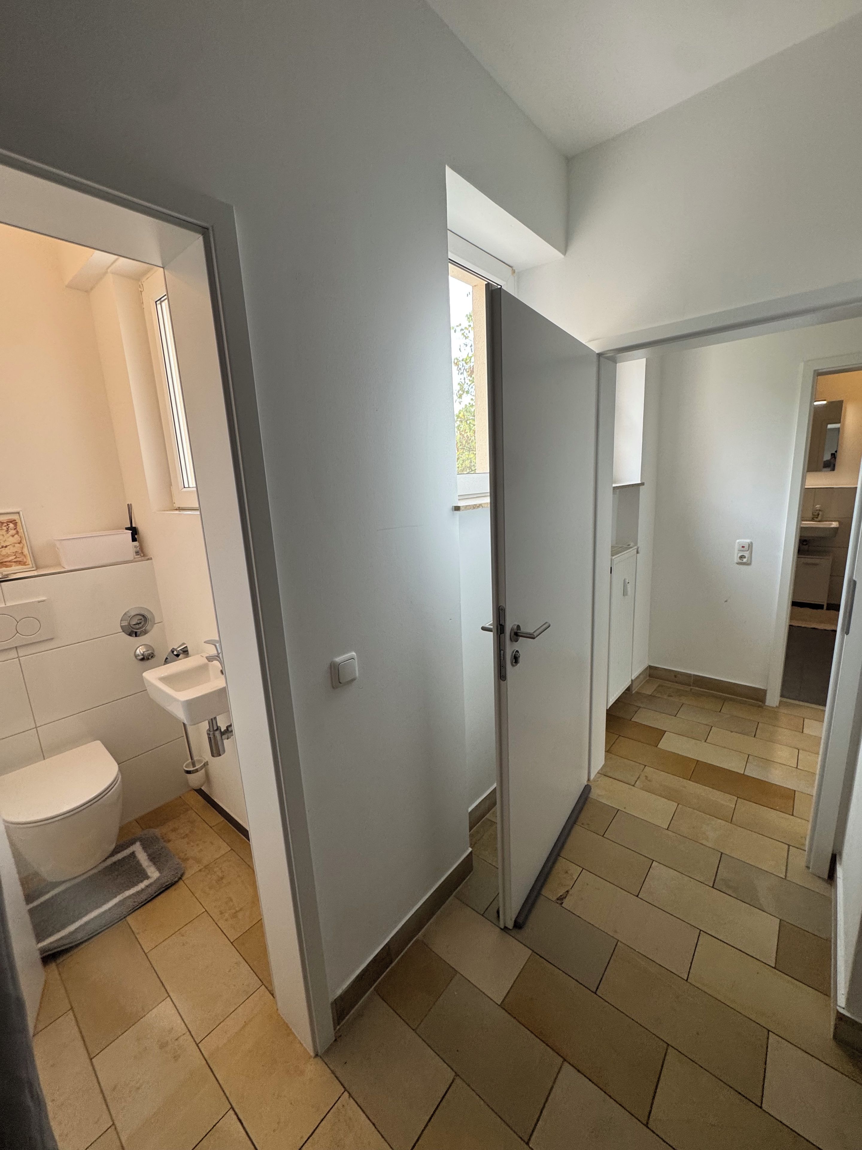 A bathroom with a toilet, sink, and window.