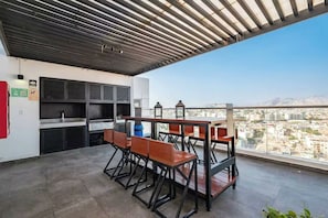 A rooftop terrace with a dining area, a grill station, and a city view. - Connect Studios by Vibrant (Barranco)
