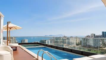 Un área de piscina en la azotea con vistas despejadas al horizonte de la ciudad y al océano.