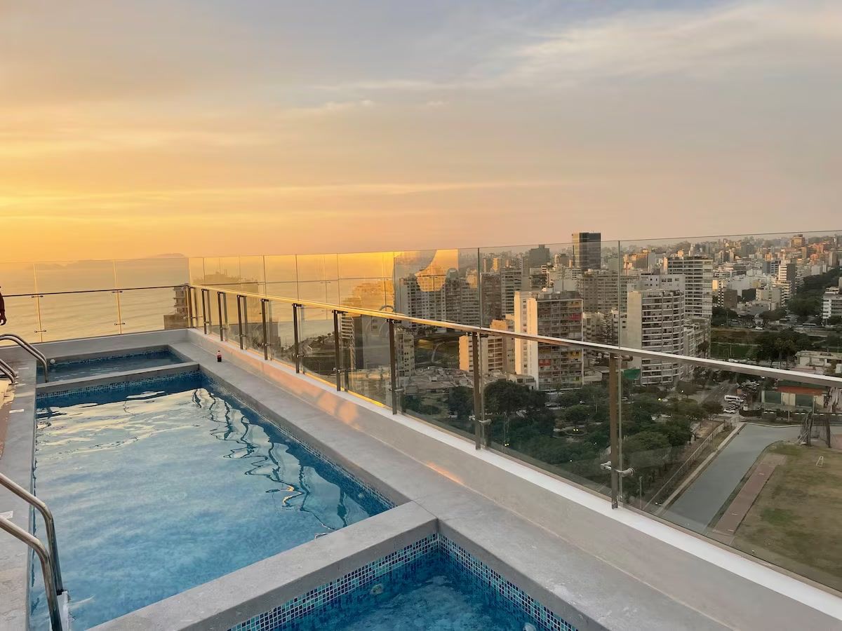 Una piscina en la azotea con vistas a la ciudad al atardecer.