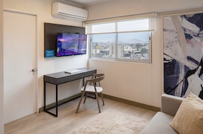 Ein modernes Zimmer mit Schreibtisch, Stuhl und einem großen Fenster mit Blick auf die Stadt.