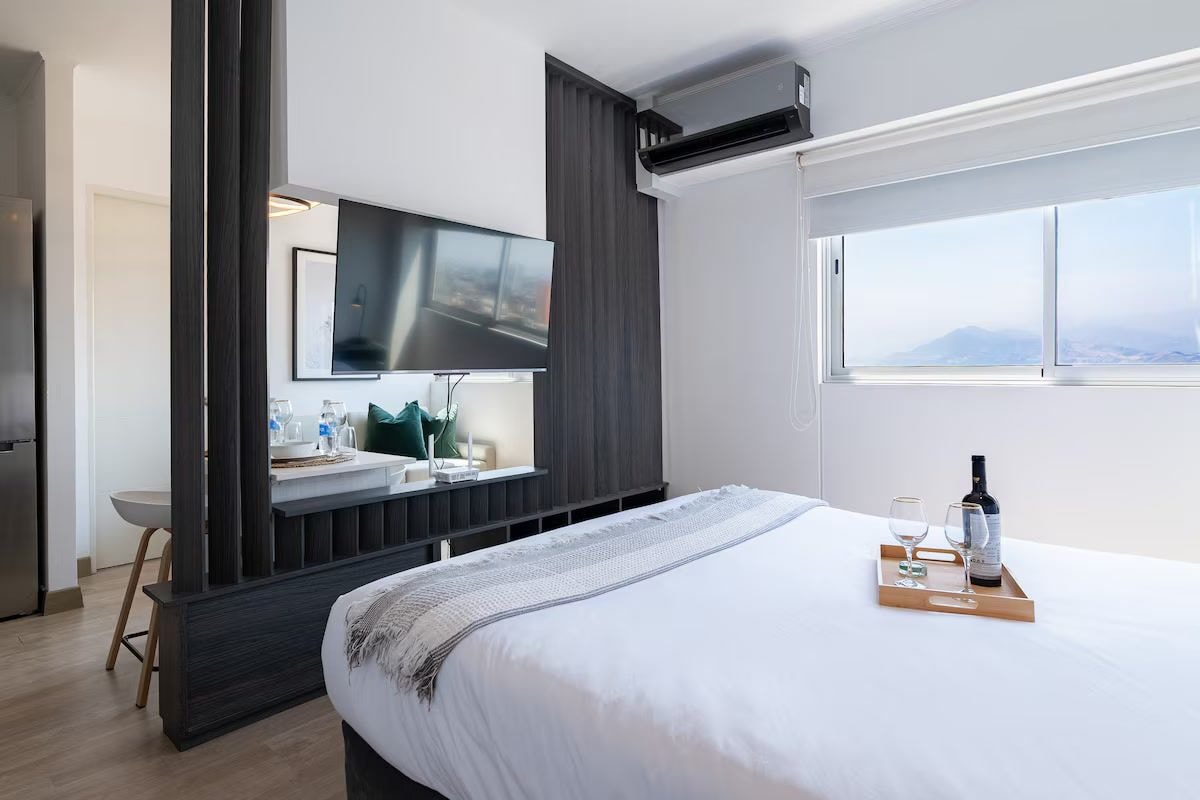 Ein Hotelzimmer mit Bett, Fernseher, Fenster mit Aussicht und einer Minibar.