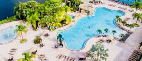 Un resort con una amplia piscina, zonas de descanso y una cancha de tenis.