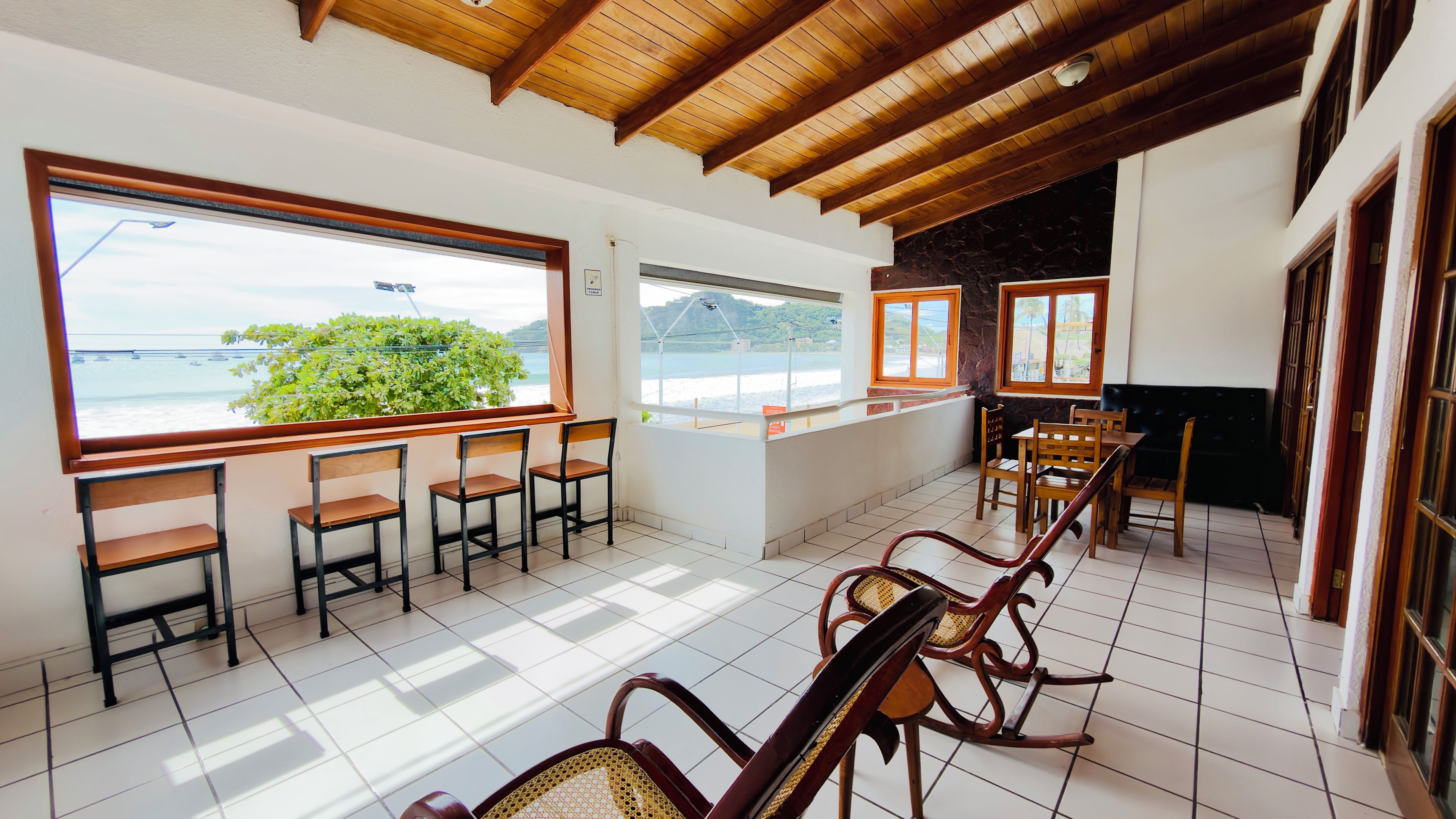 A room with a view of the sea, wooden furniture, and a tiled floor.