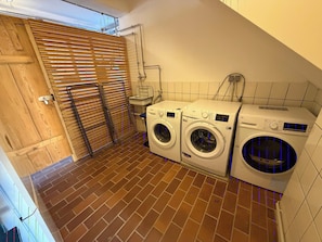 A laundry room with two front-loading washing machines, a wooden door, and a tiled floor. - Landhaus Ziemetshausen – 10 Schlafzimmer, Garten und Platz für 20 Personen (Ziemetshausen)