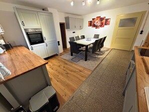 A compact kitchen with a dining area, wooden flooring, and a patterned rug. - Landhaus Ziemetshausen – 10 Schlafzimmer, Garten und Platz für 20 Personen (Ziemetshausen)