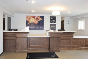 Et receptionområde med en træreception, et stort plakat og et skilt for Red Lion Inn Suites.