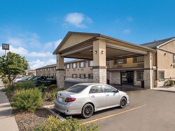 Ein Hotel mit überdachtem Parkplatz, ein Auto auf dem Parkplatz und ein Schild mit dem Hotelnamen.