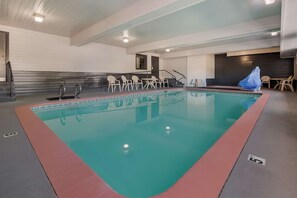 Ein Hallenbad mit roter Umrandung, umgeben von Stühlen und einem überdachten Bereich.