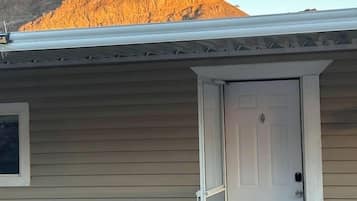 Een laag gebouw met een witte deur en een klein terras.