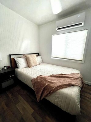A bedroom with a bed, bedside table, and an air conditioning unit. - Stunning Parker Home with River Views & Privacy! (Parker)