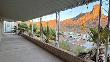 A covered balcony with a view of a mountainous landscape.