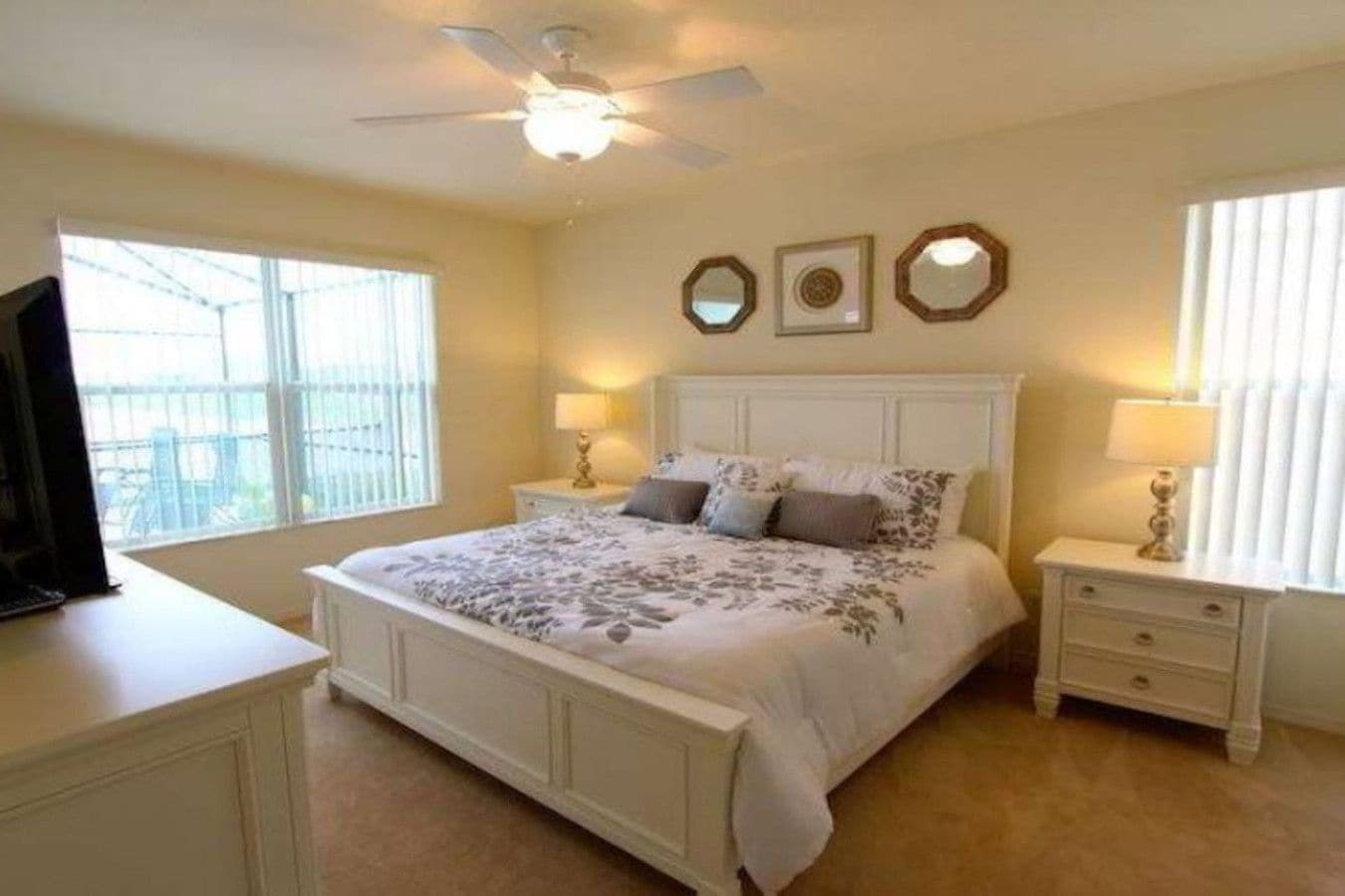 A bedroom with a bed, two bedside tables, a ceiling fan, and a window.