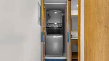 Cocina compacta con microondas y horno integrados, una pequeña encimera y una puerta de madera.