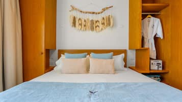 Una camera d'albergo con un letto, un armadio in legno, un accappatoio appeso e un elemento decorativo a parete.