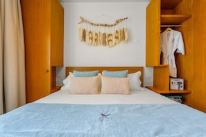 Una camera d'albergo con un letto, un armadio in legno, un accappatoio appeso e un elemento decorativo a parete.