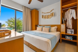 A hotel room with a large bed, a wooden wardrobe, a vanity with a mirror, and a view of the outdoors. - 1BR Condo in La Cruz de Huanacaxtle With Pool, Gym, Wifi, and AC (La Cruz de Huanacaxtle)