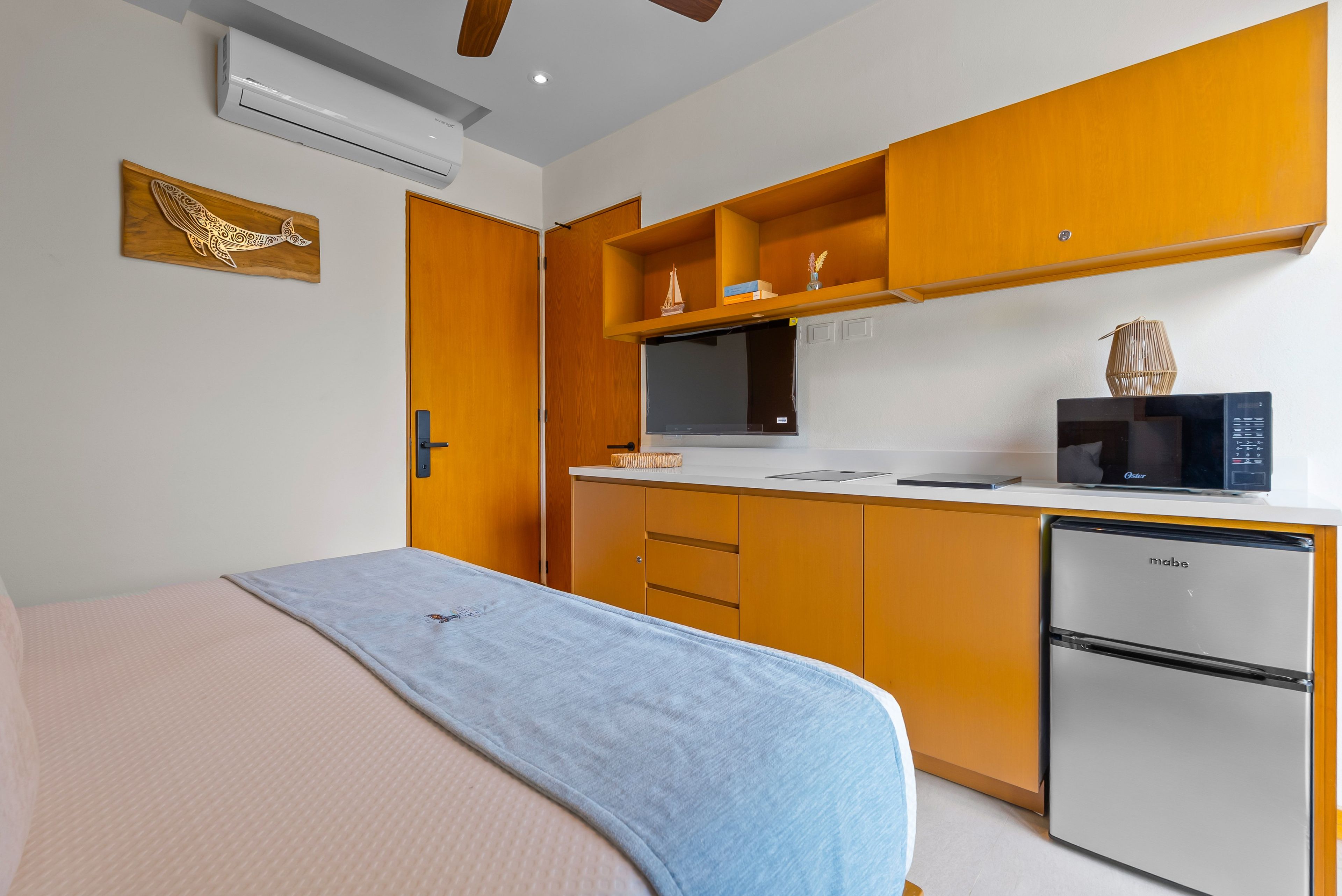 Een kleine hotelkamer met een bed, kitchenette en een kleine koelkast.