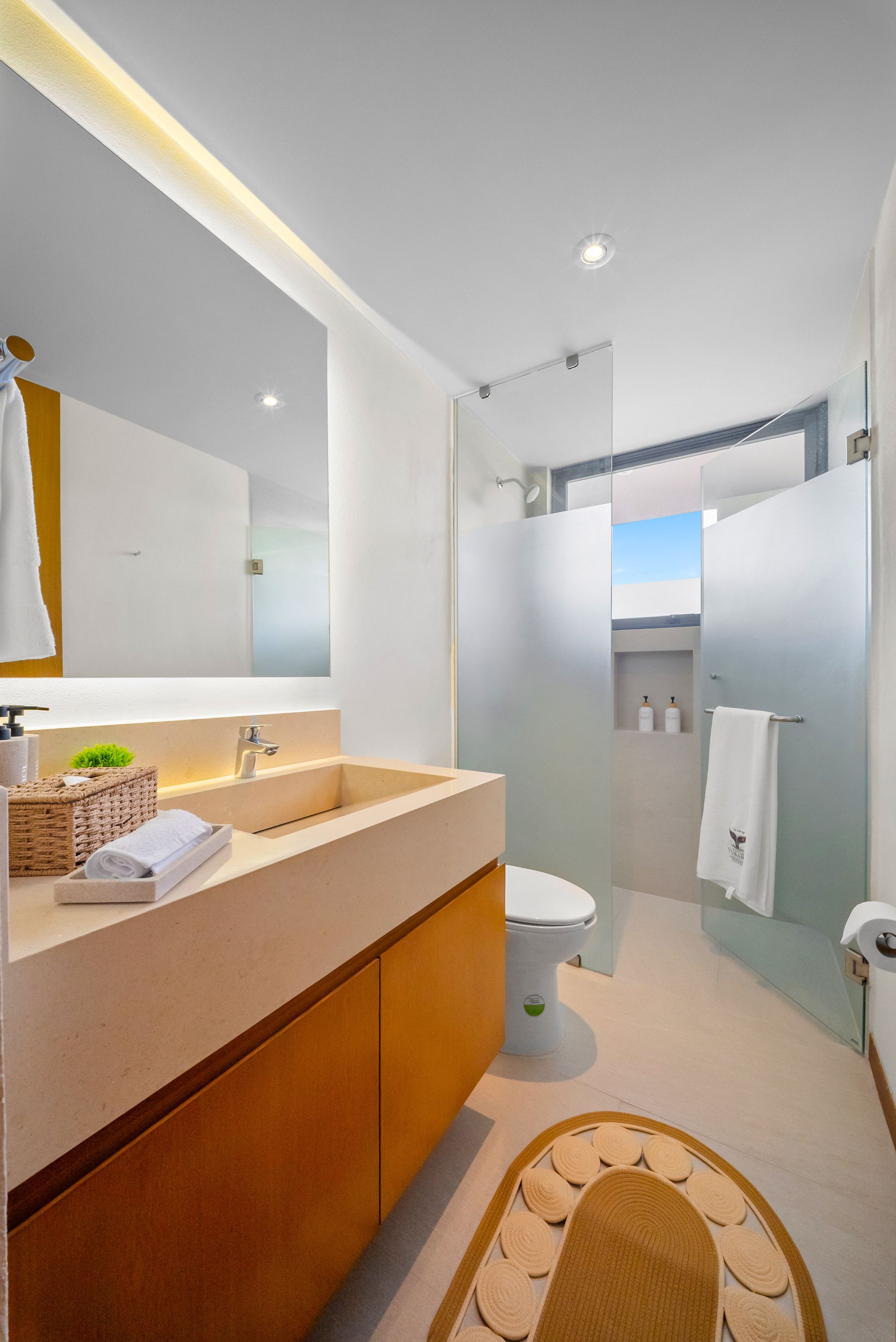 A modern bathroom with a large mirror, a sink, and a toilet.