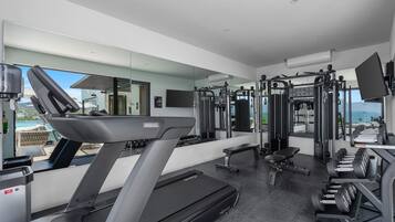 Une salle de sport moderne équipée d’un tapis de course, d’appareils de musculation et d’un banc.