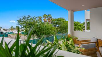 Un balcon avec vue sur un port de plaisance, du mobilier d’extérieur et une végétation luxuriante.