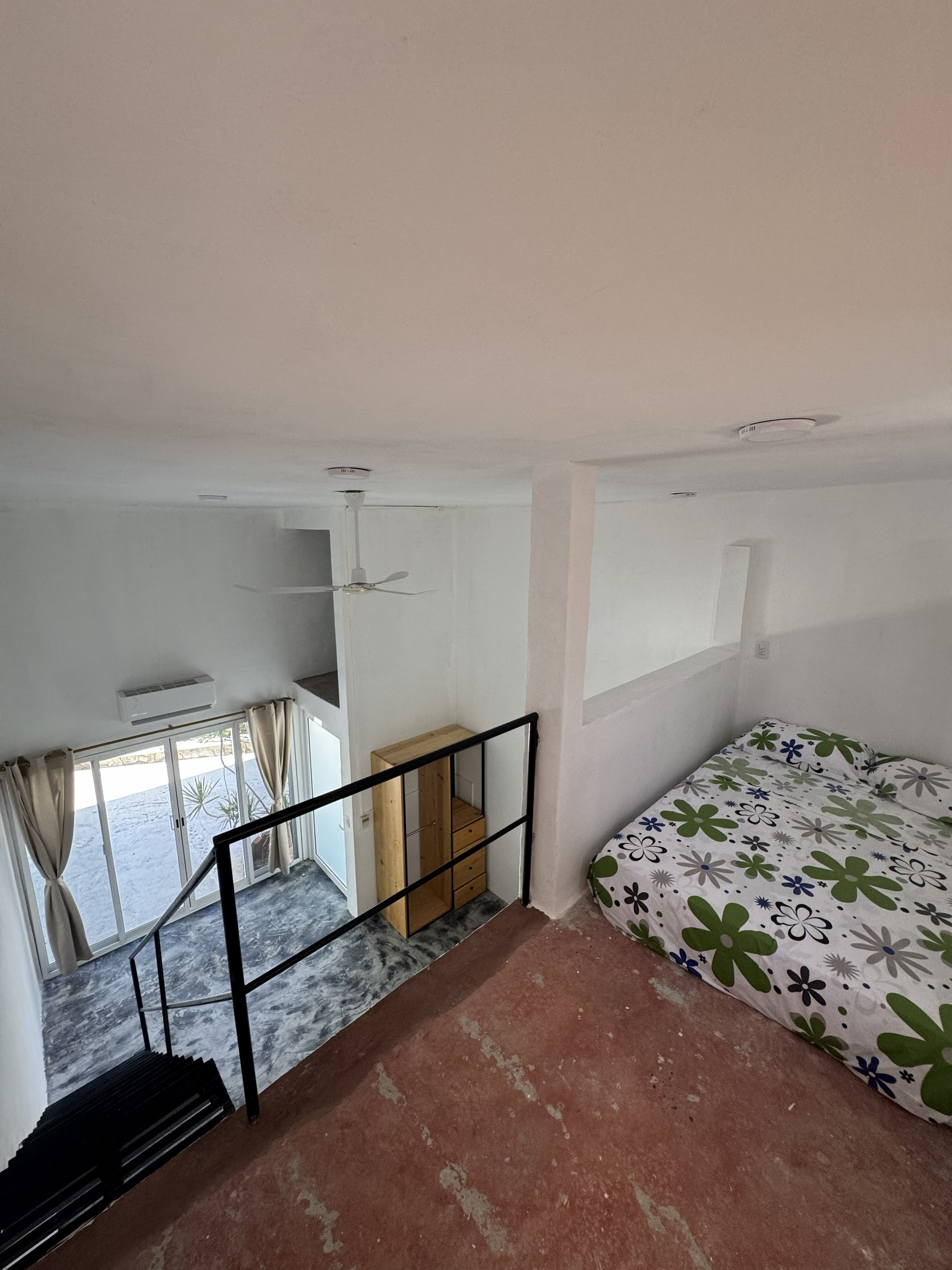Un dormitorio con cama, ventana, escalera y armario de madera.