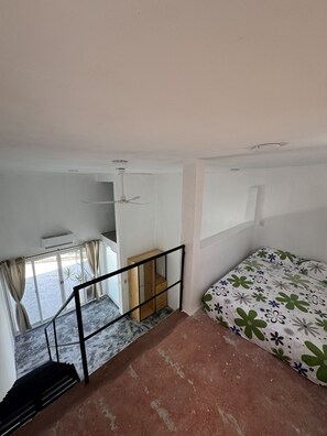 A bedroom with a bed, a window, a staircase, and a wooden wardrobe. - Ruby & Antonella (San Pedro Pochutla)