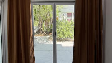 Una habitación con puerta corrediza de vidrio, cortinas marrones y un equipo de aire acondicionado instalado en el techo.